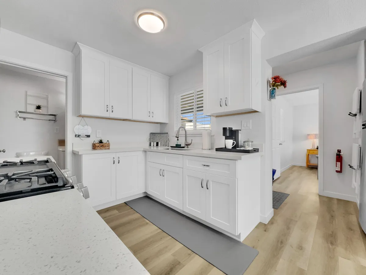 A kitchen view focusing on the countertop, stove, coffee maker, and a window that lets in abundant natural light. The arrangement suggests a cozy spot for brewing coffee and enjoying the sunshine.