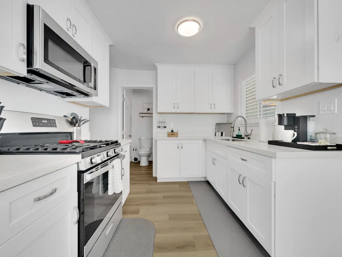 A crisp, modern kitchen featuring stainless steel appliances, white cabinetry, and a central kitchen island. The space appears uncluttered and inviting, perfectly set up for meal preparation and socializing.