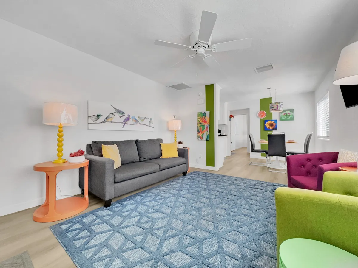 A vibrant living space with a gray sofa, colorful accent chairs, and bold artwork on the walls. The playful and energetic vibe matches the lively feel of downtown Mesa, making this an ideal gathering spot for groups before or after a night out.